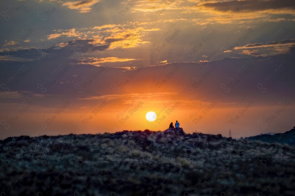 silhouette couple sitting on the top of a hill looking at the sunset from Taif National Park, Taif, Saudi Arabia