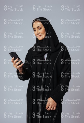 A Saudi young woman interacts with his phone with different expressions