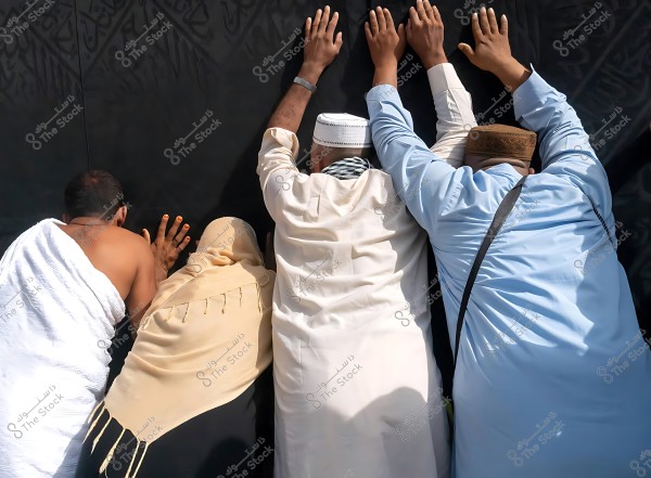 A group of people touching the Kaaba\'s covering with their fingertips during the Hajj pilgrimage.