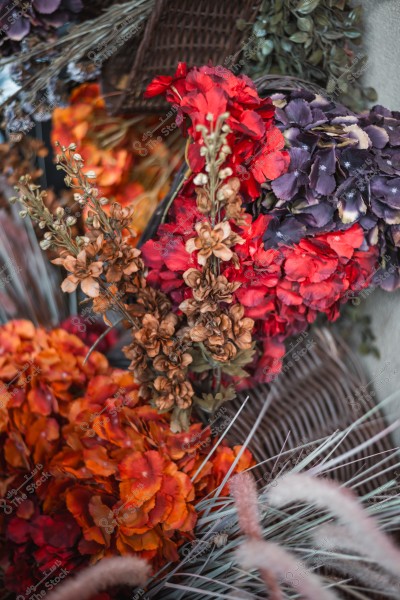 Elegant arrangement of multi-colored dried flowers, including red, orange, and purple blossoms, with detailed dry leaves and a wicker basket.