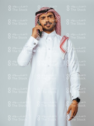 بورتريه رجل سعودي يرتدي الزي السعودي التقليدي يتحدث بالجوال ويظهر على وجهه الانزعاج، شاب يجري مكالمة هاتفية