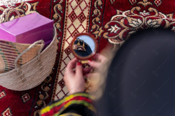 A shot of a Saudi woman whose eyes are reflected from the mirror wearing the traditional Saudi dress that represents the folklore, the day of foundation, the Saudi culture.