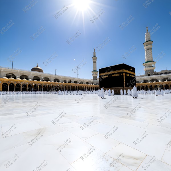 Image of the courtyard of the Grand Mosque in Mecca, Saudi Arabia, featuring the Kaaba at the center surrounded by a large number of worshippers dressed in white ihram clothing. The mosque is seen with its domes and minarets at the sides, all under a bright sun in a clear blue sky.