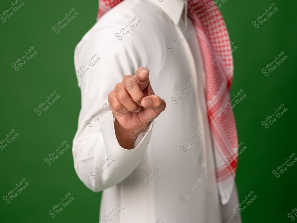 شخص يرتدي الزي السعودي التقليدي ويتحرك بإصبعه على خلفية خضراء.