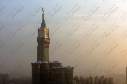 صورة لبرج الساعة في وقت الغروب في مكة المكرمة، والسماء ملبدة بالغيوم.