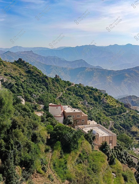 A scenic view of green-covered mountains with a traditionally designed house situated on a hillside. In the background, multi-layered mountains create a stunning panoramic view under a clear blue sky. Narrow roads wind through the hills, indicating a rural area.