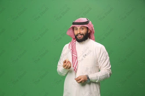 بورتريه رجل سعودي يرتدي الزي السعودي التقليدي يتناول الحلوى