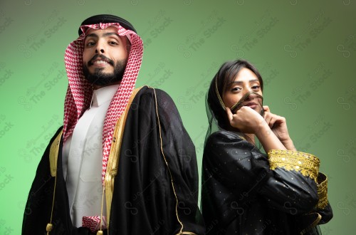 رجل سعودي يرتدي الزي السعودي وامرأه سعودية ترتدي المخنق والزي السعودي التقليدي الشعبي للمناسبات والإحتفالات الوطنية على خلفية خضراء