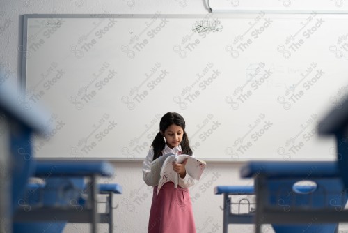 A Saudi student wears a school uniform and does different interactions and shows the tables in the classroom