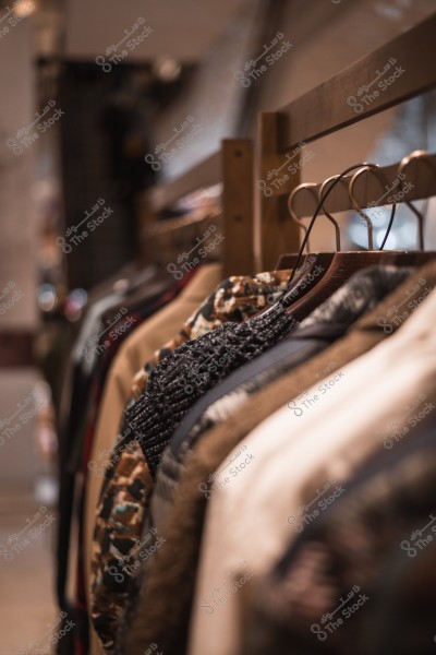 A side view of several jackets hanging on wooden hangers in a clothing store.