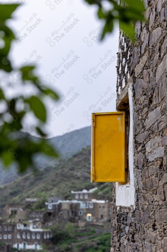 An ancient building built of medium stones, windows surrounded by white paint while the sky looks cloudy at sunset, Rijal Almaa heritage village in the Asir region