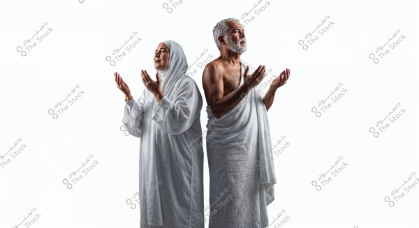 صورة لرجل وامرأة يرتديان ملابس الإحرام البيضاء, ويقفان بجانب بعضهما البعض, يرفعان أيديهما في وضع الدعاء. المرأة ترتدي حجابًا يغطي الرأس, بينما الرجل لديه لحية قصيرة وشعر رمادي. الملابس تمثل الإحرام الذي يُرتدى من قِبل المسلمين أثناء أداء مناسك الحج أو العمرة. خلفية الصورة بيضاء بالكامل, تعكس روحانية اللحظة.