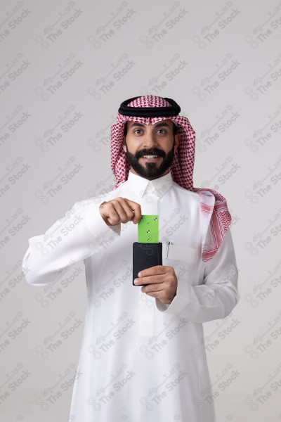 بورتريه رجل سعودي يحمل بطاقة خضراء على خلفية بيضاء