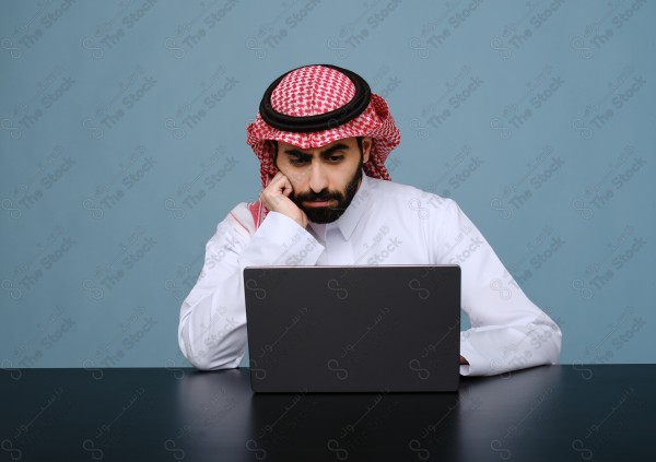 بورتريه شاب سعودي يرتدي الزي السعودي يستخدم جهاز المحمول ويتفاعل معه ، يقف على خلفية سماوية،