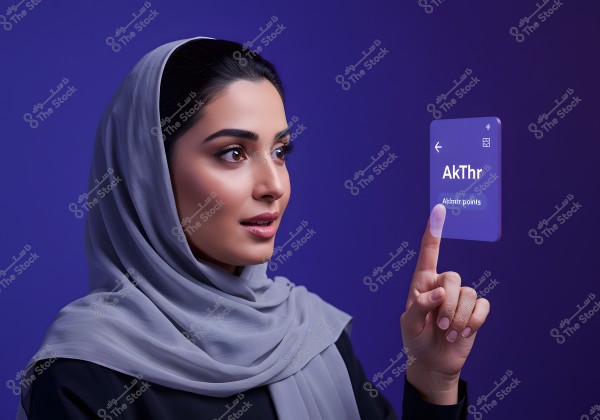A portrait of a woman wearing a gray hijab, interacting with a virtual transparent screen. She is dressed in a black abaya, with a blue background. The focus is on engaging with modern technology.\r\n\r\n###
