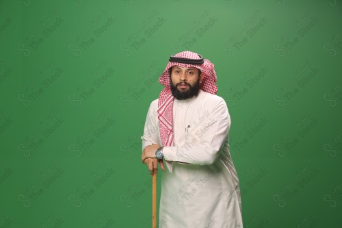 بورتريه رجل سعودي يرتدي الزي السعودي التقليدي يتكئ على العصا أثناء أداء رقصة المزمار الحجازية