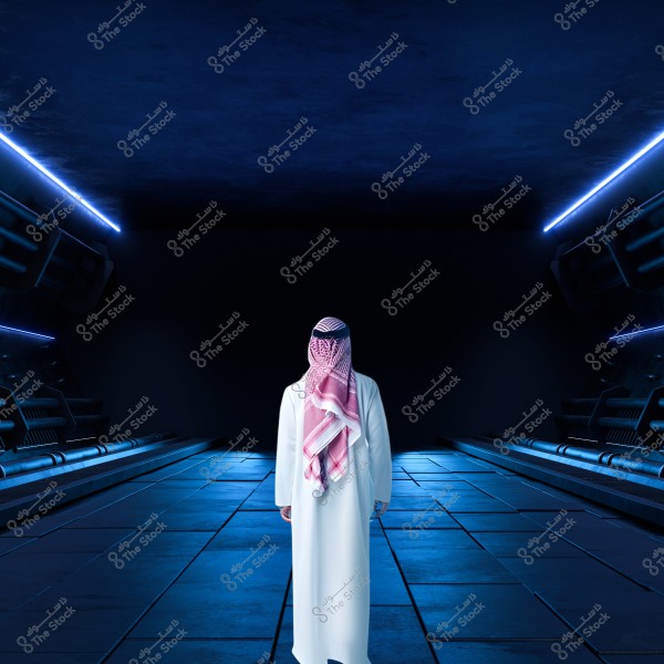 The image shows a person wearing traditional clothing, a thobe and a ghutra, standing in the middle of a modern corridor illuminated with blue lights. The walls and ceiling have futuristic design elements, giving the impression of being in a technologically advanced or space-themed location.