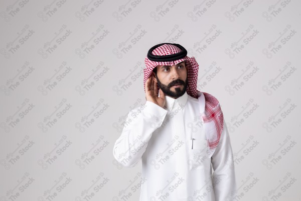 بورتريه رجل سعودي يقف على خلفية بيضاء ويشير بيده اتجاه معين