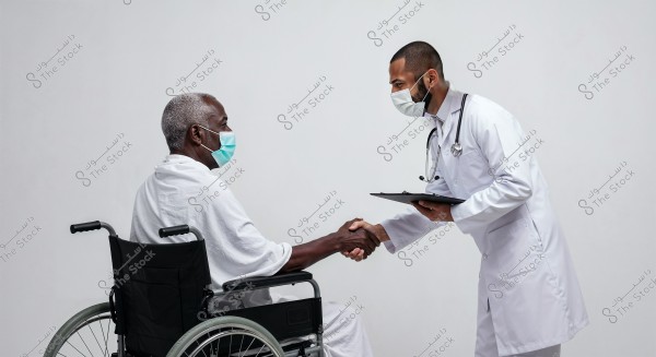 Image of a man sitting in a wheelchair, wearing white attire and a face mask, shaking hands with a doctor in a white medical coat and mask. The doctor is holding a clipboard and appears to be providing medical care or advice.