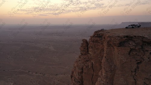 لقطة جوية لمجموعة سياح على جبل من جبال طويق المسمى بحافة العالم. سلسلة من الجبال الصخرية