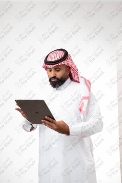 بورتريه رجل سعودي يحمل بيده الآيباد و ينظر لشاشته ويقوم بتعابير مختلفة، خلفية بيضاء