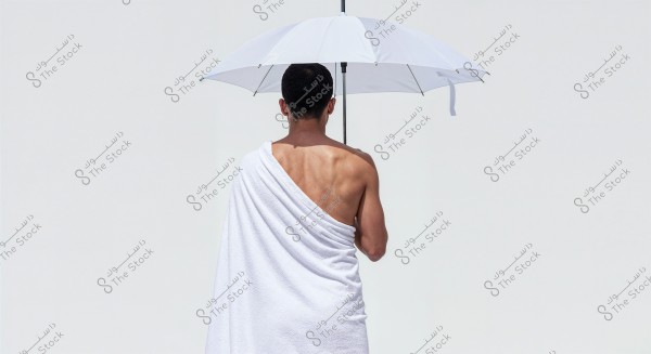 ** An image of a man with bare shoulders and an exposed back, wearing a white wrap and holding a white umbrella. The background is white, giving a sense of simplicity and elegance. This attire might suggest traditional clothing associated with specific occasions.\r\n\r\n**