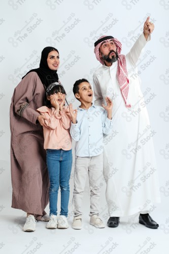 Portrait of a Saudi family looking towards a place, two children standing next to their parents pointing towards a goal, signs of happiness, a happy family atmosphere, the concept of a happy family, spending enjoyable family times