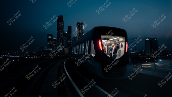 قطار يسير في المساء مع خلفية أفق المدينة المضيئة.