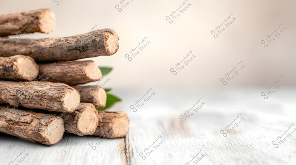 The image features a collection of miswak sticks arranged horizontally on a white wooden surface. The atmosphere is neutral with a blurred background that includes a hint of green leaves.