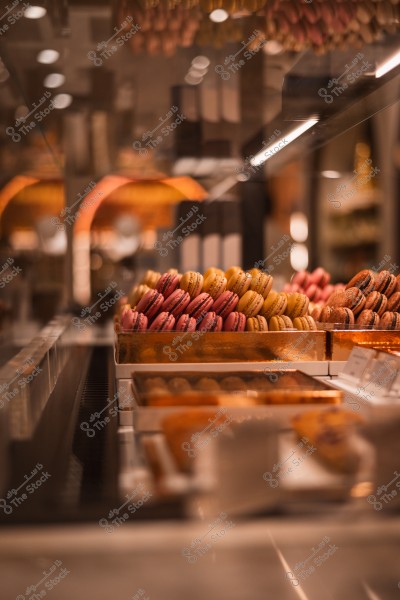 صف من حلوى الماكارون بألوان مختلفة معروضة في متجر حلويات أنيق.