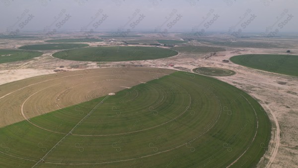 Aerial view of a circular agricultural field with a center pivot irrigation system in a semi-arid region.