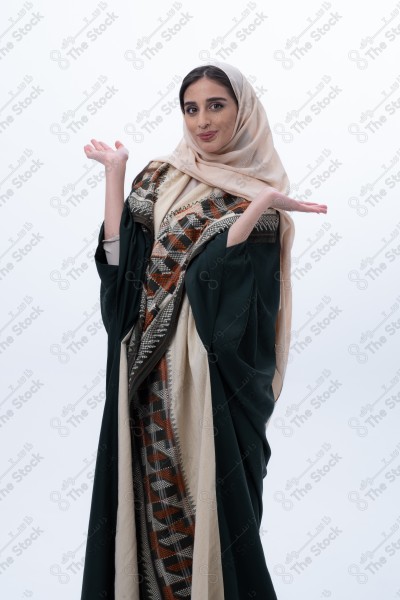 Portrait of a young Saudi woman wearing an abaya and hijab, with a smiling facial expression, standing against a white background