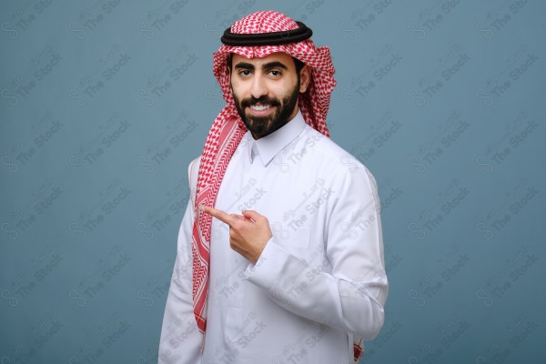 بورتريه شاب سعودي يرتدي الزي السعودي يقوم بالتفاعل بيدية ، ويظهر بتعابير وجه، على خلفية سماويه