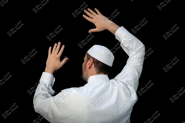 A man wearing a white shirt and a white cap raises his hands against a Kaaba.