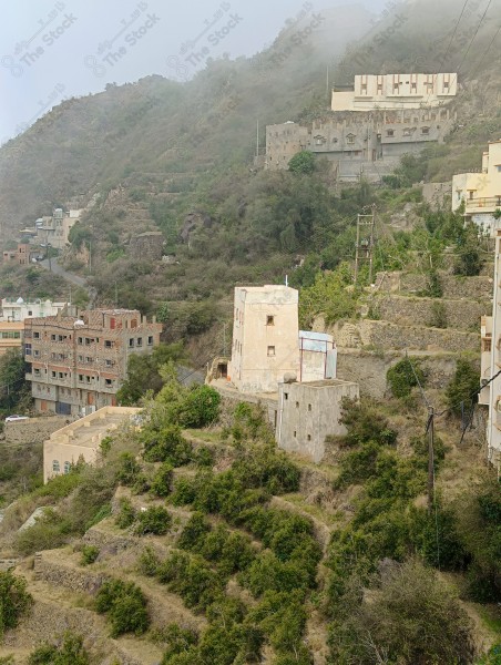 A group of houses on a mountain in Fifa Governorate surrounded by agricultural terraces during the day, nature in Saudi Arabia.