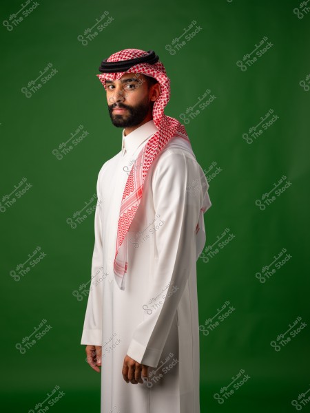 An Arab man wearing a thobe, ghutra, and agal against a green background.