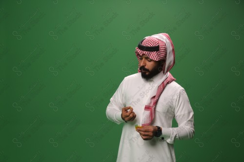 بورتريه رجل سعودي يرتدي الزي السعودي التقليدي يتناول الحلوى