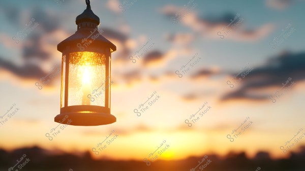 A traditional metal lantern, illuminated, hangs in the foreground of the image, with a sunrise in the background featuring warm color gradients in the sky. The clouds are scattered and slightly blurred, adding a sense of calm and tranquility to the scene.