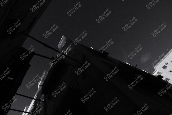 منظر لأبنية قديمة تظهر بشكل مائل في صورة بالأبيض والأسود تحت سماء مظلمة.