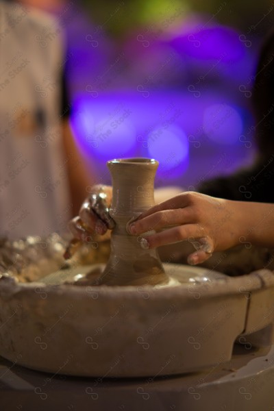 A Saudi girl wearing an abaya makes pottery in the workshop and shows her hand full of clay, a handicraft