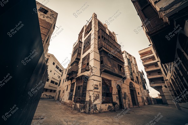 Here’s the translation of your text into English:\r\n\r\n\"A historical image of Jeddah showing a traditional multi-story building at the corner, clearly displaying its unique architectural design with stone and wooden balconies. The surrounding buildings appear slightly worn, giving the area a historical character. The streets are cobblestone, with a wooden chair in front of the central building, and a palm tree visible in the background.\"\r\n\r\nIf you want, I can also make a slightly more **natural, descriptive English version** that reads like a guidebook or historical caption. Do you want me to do that?\r\n