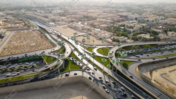 تصوير جوي لحركة سير السيارات على الطريق السريع في مدينة الرياض، الفن الهندسي المعماري للمجسمات الفنية على شكل أشجار خضراء، الطرق المتقاطعة في دوار عرقة بالمملكة العربية السعودية، البنية التحتية المتطورة