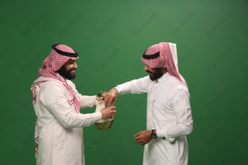 رجل سعودي يرتدي الزي السعودي التقليدي يقدم لضيفه القهوة السعودية في أحد المناسبات