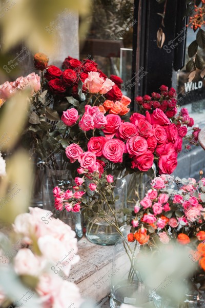 Bouquets of colorful flowers, including red and pink roses, displayed in a flower shop.