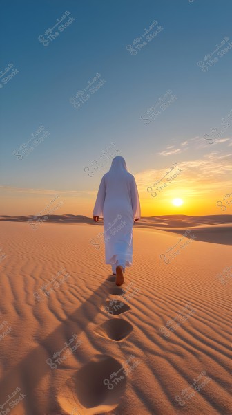 An image of a person wearing a white robe walking through a vast desert at sunset. The sky displays beautiful shades of blue and orange as the sun sets on the horizon. The wind\'s effect is visible on the sand, creating gentle waves, and the person\'s footsteps are clearly marked behind them.