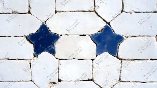 A close-up image of a wall made of white tiles featuring two blue stars. The tiles are slightly worn and cracked, giving the wall a traditional or vintage appearance. The tile design showcases an artistic geometric pattern.