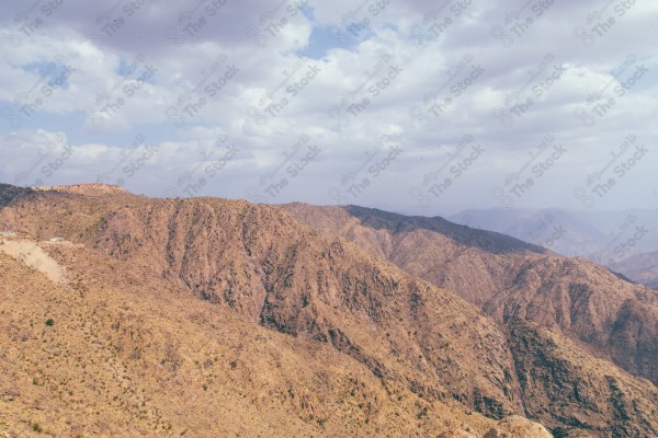 لقطة لجبال محافظة عسير تحيط بها مدرجات زراعية وتظهر السماء شبه غائمة نهارًا، اشجار وغابات، الطبيعة في السعودية