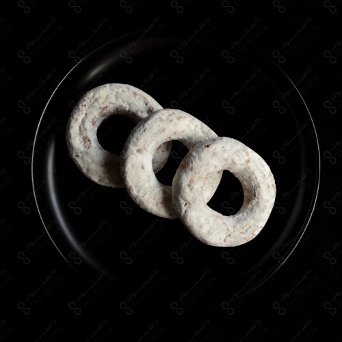 A shot of a plate in a group of donuts on a black background, pastries.