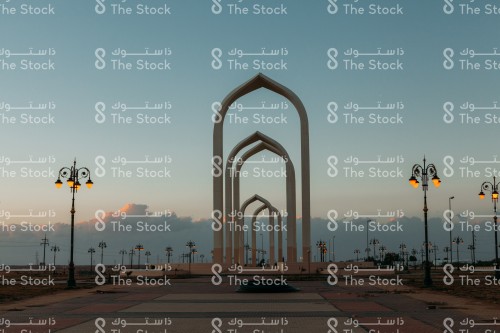 مجسم بوابة تبوك محاط بمجموعة من المصابيح المضيئة أثناء غروب الشمس