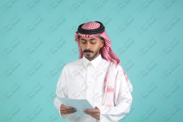 رجل سعودي يرتدي الزي السعودي يمسك بالاوراق،  يتحدث ويشرح فكرة العمل، اعمال مكتبية